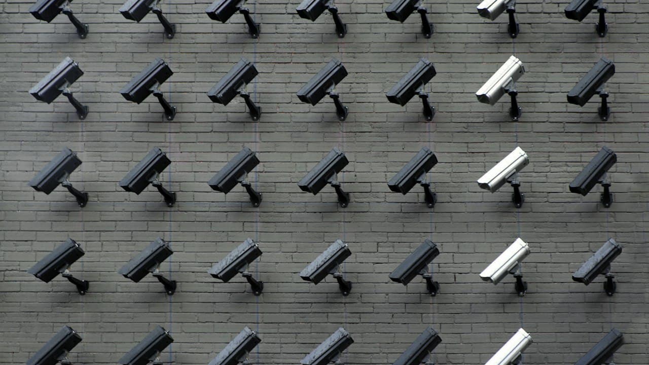 Security and surveillance cameras against a clear sky